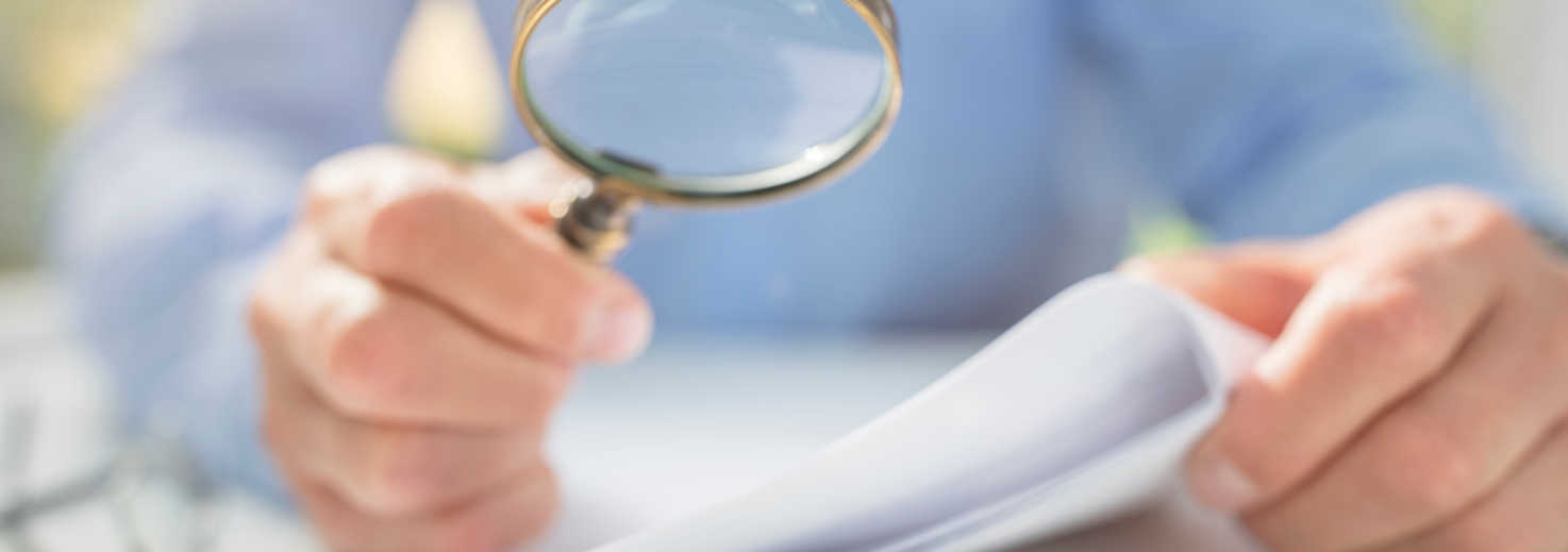 Person holding paper and magnifying glass