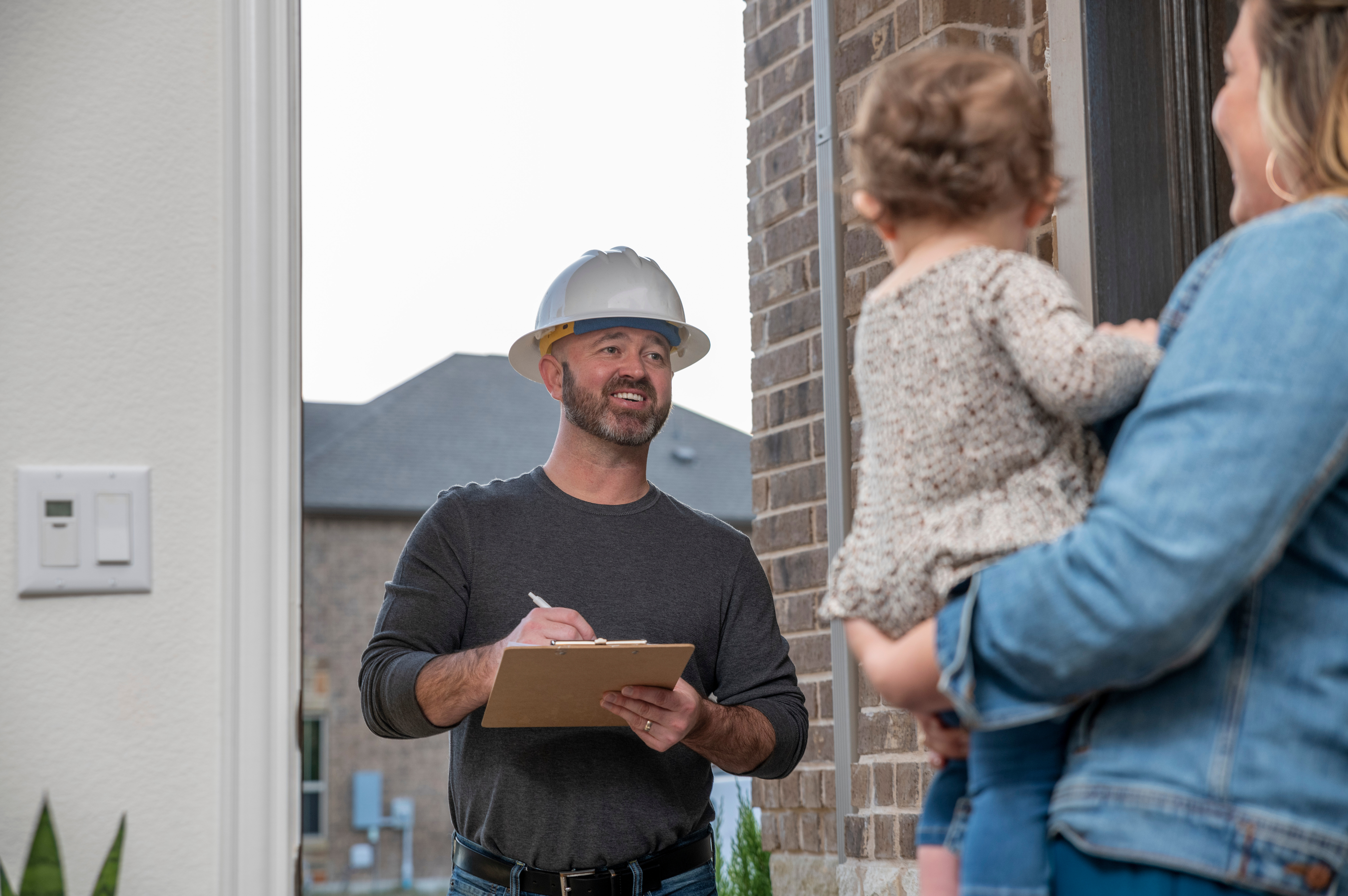 A man in a hard hat talking to a woman and child